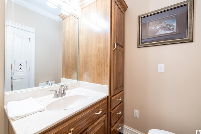 bathroom with ornamental molding, vanity, and toilet