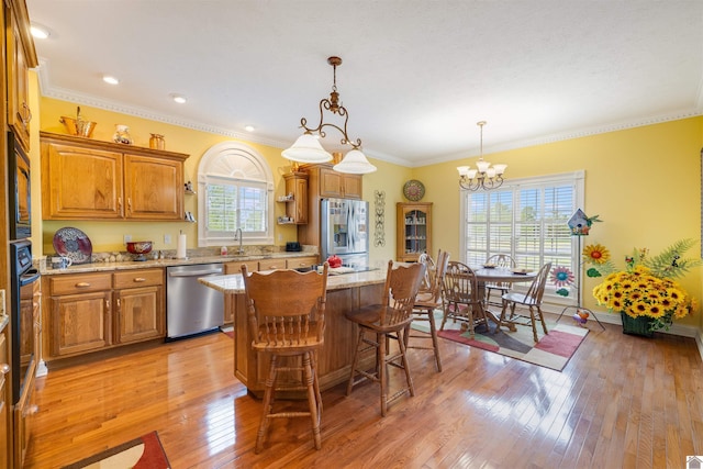 kitchen with a wealth of natural light, stainless steel appliances, light hardwood / wood-style floors, and a kitchen island