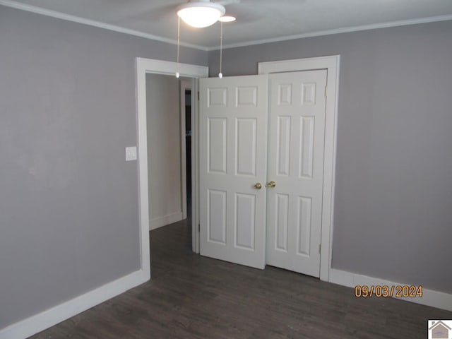 unfurnished bedroom featuring a closet, dark hardwood / wood-style floors, and ornamental molding