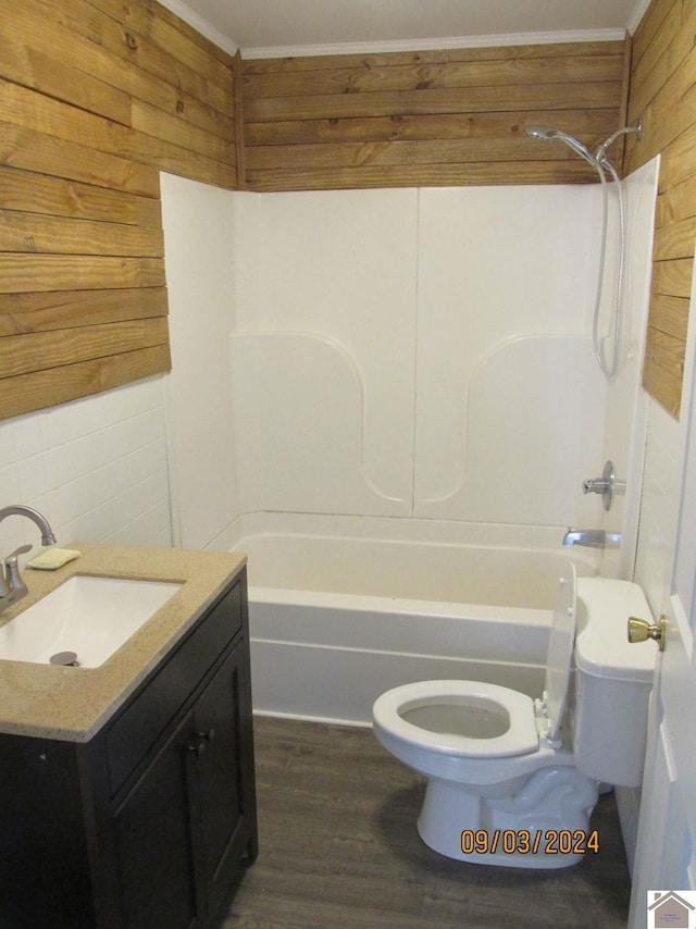 full bathroom featuring toilet, wood-type flooring, wood walls, washtub / shower combination, and vanity