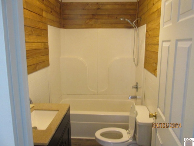 full bathroom with shower / tub combination, toilet, wooden walls, and vanity