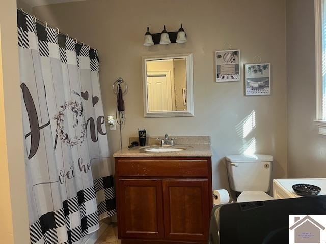 bathroom featuring curtained shower, toilet, and vanity