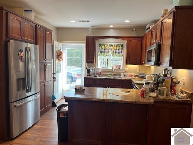 kitchen featuring stainless steel appliances, sink, kitchen peninsula, and light hardwood / wood-style flooring