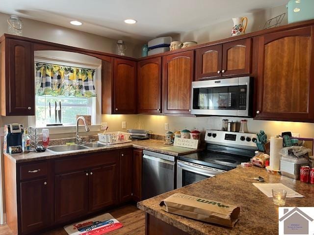 kitchen with appliances with stainless steel finishes, wood-type flooring, and sink