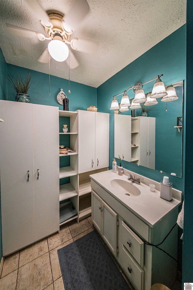 bathroom with tile patterned floors, ceiling fan, vanity, and a textured ceiling