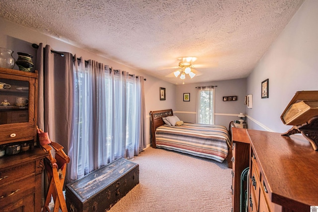 carpeted bedroom featuring ceiling fan and a textured ceiling