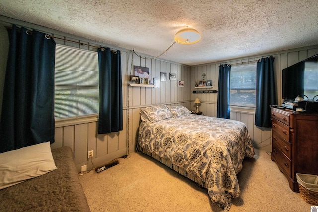 bedroom with light colored carpet, a textured ceiling, and wooden walls