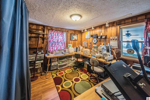 office with a textured ceiling, hardwood / wood-style floors, and wood walls