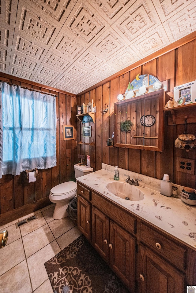 bathroom with toilet, wooden walls, and vanity