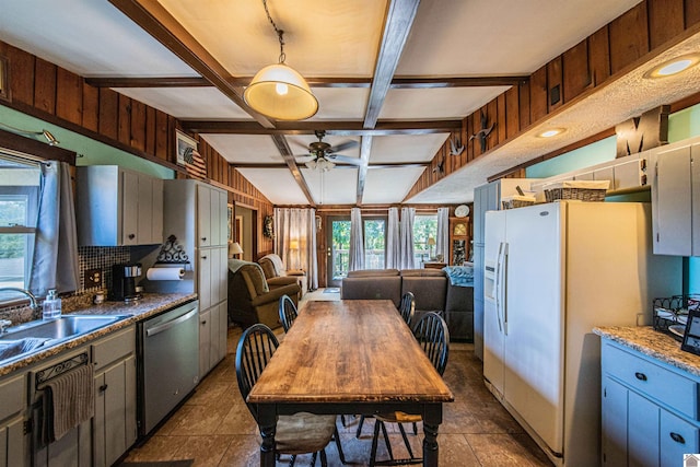 kitchen featuring dishwasher, white refrigerator with ice dispenser, sink, ceiling fan, and beam ceiling