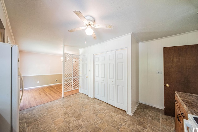 unfurnished bedroom featuring white fridge, ornamental molding, a textured ceiling, ceiling fan, and a closet