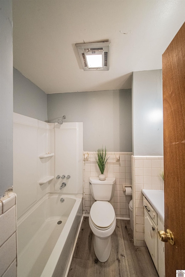 full bathroom with toilet, vanity, shower / bathtub combination, tile walls, and hardwood / wood-style flooring