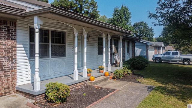 view of exterior entry with a lawn and covered porch