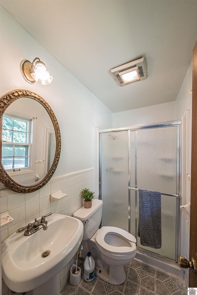 bathroom featuring walk in shower, tasteful backsplash, tile walls, toilet, and sink