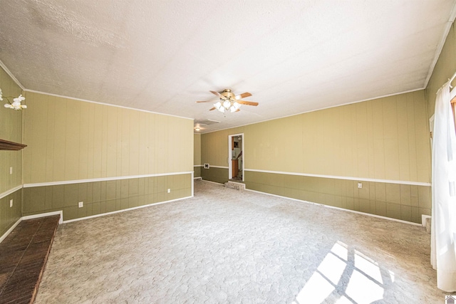 unfurnished room featuring a textured ceiling, ceiling fan, and wooden walls