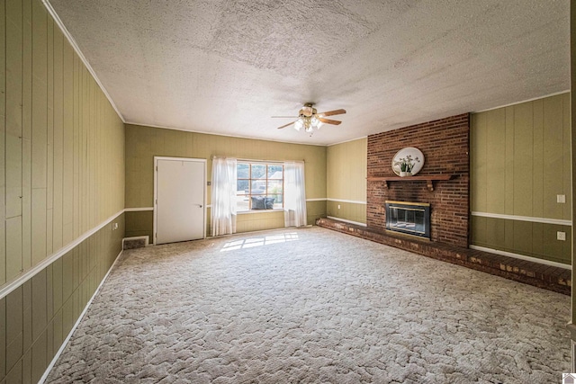 unfurnished living room featuring a fireplace, wood walls, ceiling fan, and carpet floors