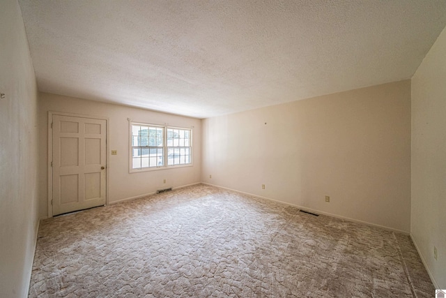 carpeted empty room featuring a textured ceiling