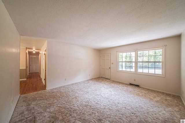 carpeted empty room with a textured ceiling