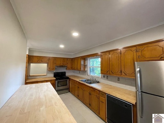 kitchen with appliances with stainless steel finishes, sink, decorative backsplash, butcher block counters, and ornamental molding