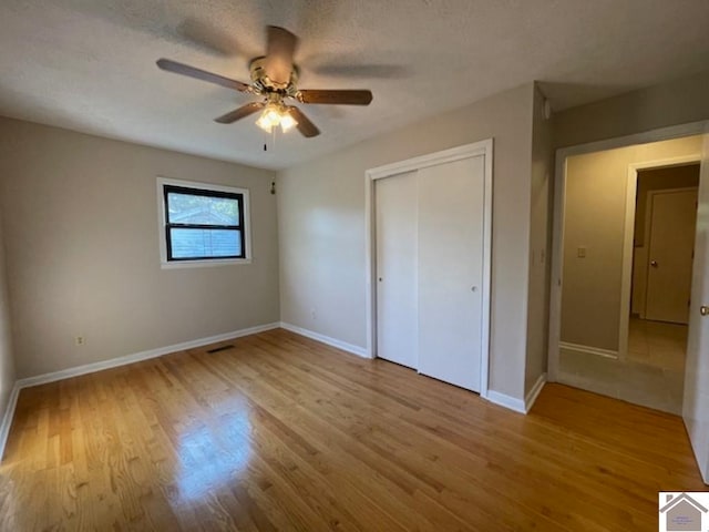 unfurnished bedroom with light wood-type flooring, a closet, ceiling fan, and a textured ceiling