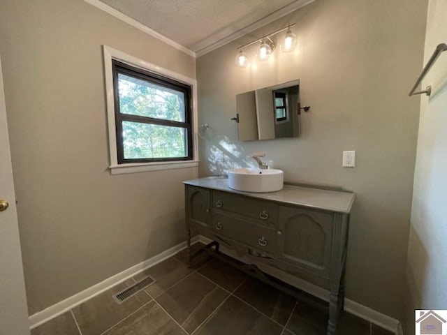 bathroom featuring a textured ceiling, vanity, tile patterned floors, and crown molding