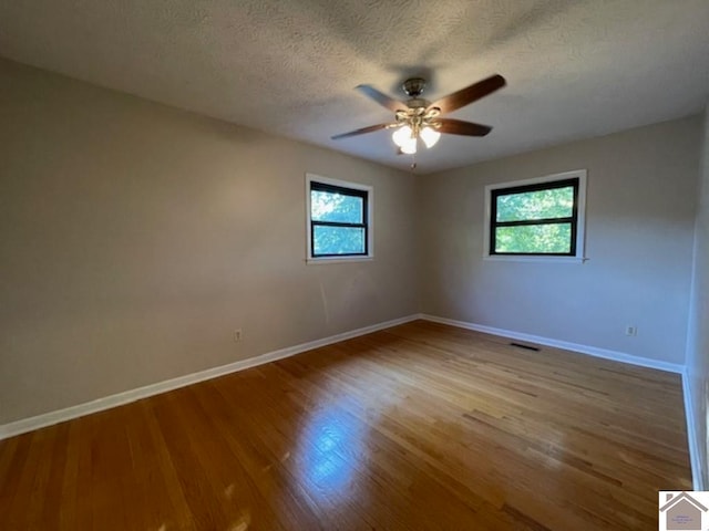 spare room with ceiling fan, light hardwood / wood-style floors, a textured ceiling, and a healthy amount of sunlight