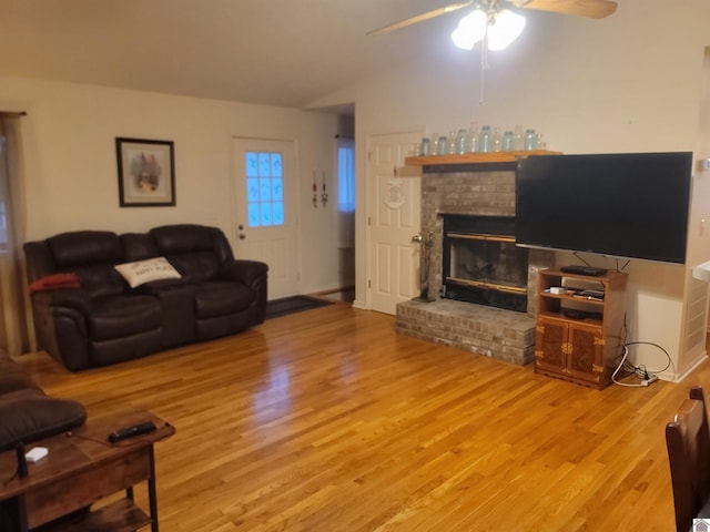 living room featuring light hardwood / wood-style floors, ceiling fan, vaulted ceiling, and a fireplace