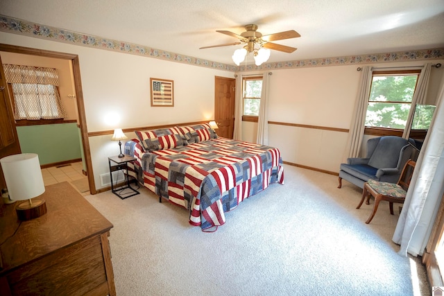 carpeted bedroom featuring multiple windows, ceiling fan, and a textured ceiling