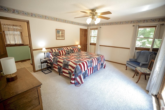 bedroom with ceiling fan, baseboards, light colored carpet, and multiple windows