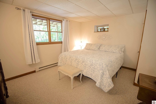 bedroom with a baseboard heating unit, a drop ceiling, and carpet