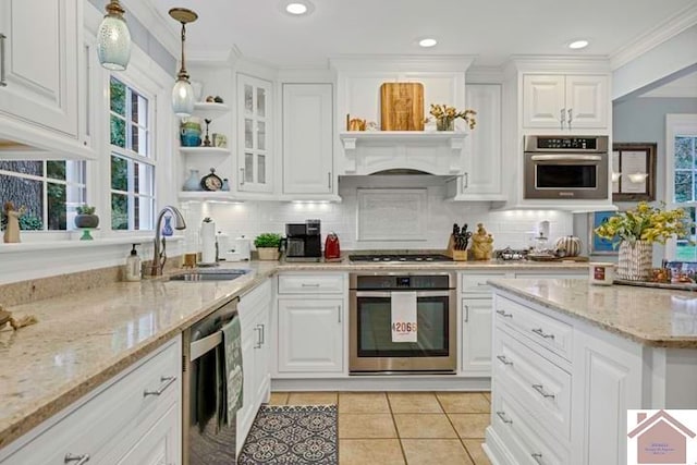 kitchen with hanging light fixtures, sink, white cabinetry, stainless steel appliances, and light stone countertops