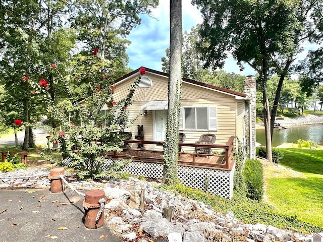 back of property with a lawn and a deck with water view