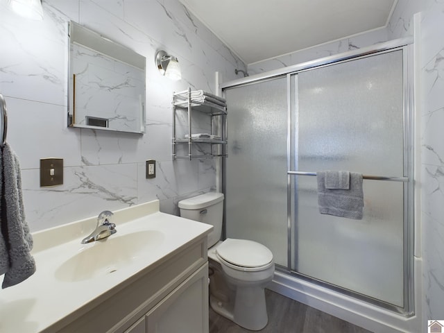 bathroom featuring vanity, wood-type flooring, tile walls, toilet, and a shower with door