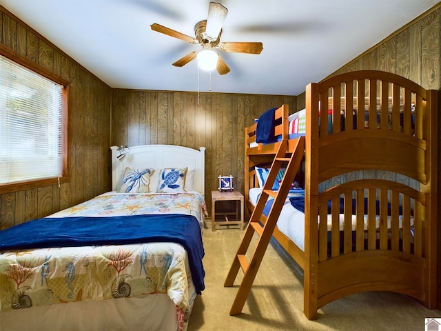 bedroom with carpet, wood walls, and ceiling fan