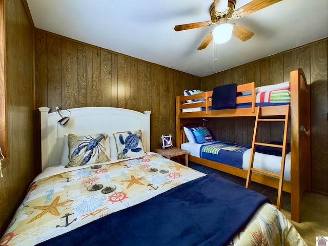 bedroom featuring wooden walls, carpet, and ceiling fan