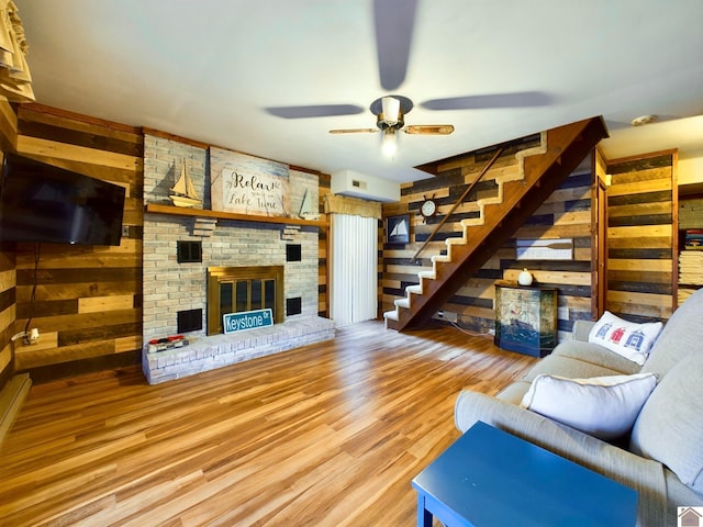 living room featuring a fireplace, wood walls, hardwood / wood-style floors, and ceiling fan