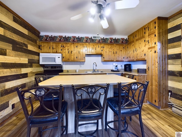 kitchen featuring wooden walls, hardwood / wood-style floors, ceiling fan, and range with electric stovetop