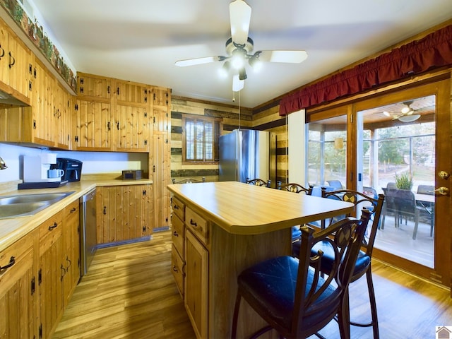 kitchen with ceiling fan, sink, a kitchen island, light hardwood / wood-style flooring, and appliances with stainless steel finishes