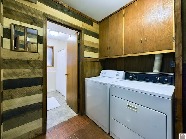 laundry area with wood walls, independent washer and dryer, and cabinets