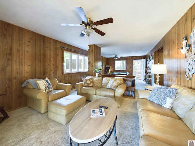 carpeted living room featuring ceiling fan and wood walls