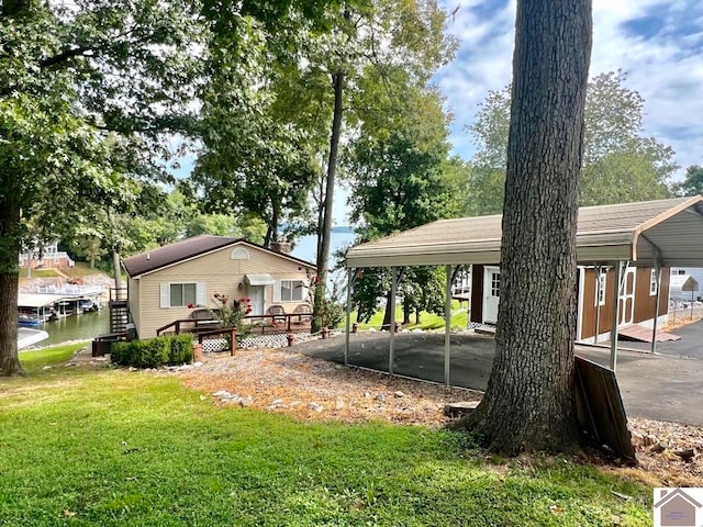 exterior space with a deck with water view, a carport, and a yard