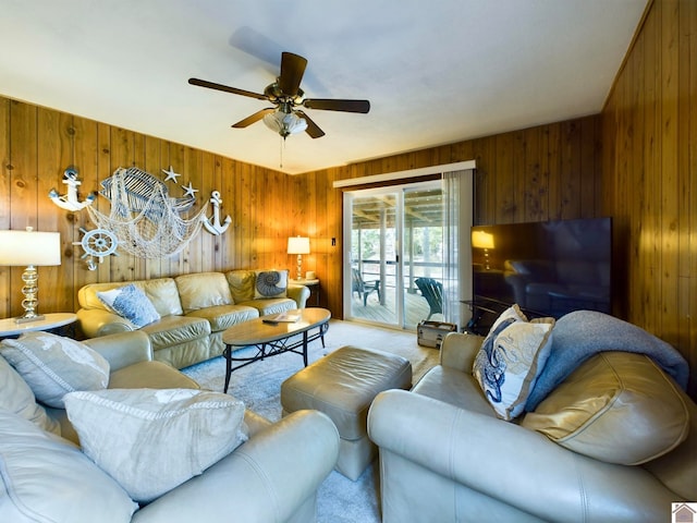 living room featuring wood walls, ceiling fan, and light colored carpet