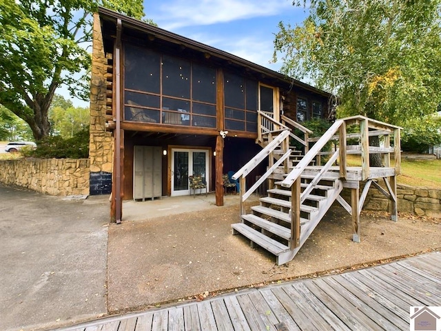 back of house with a wooden deck and a patio