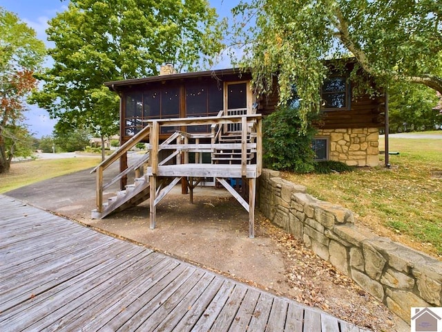 rear view of property with a deck, a yard, and a sunroom