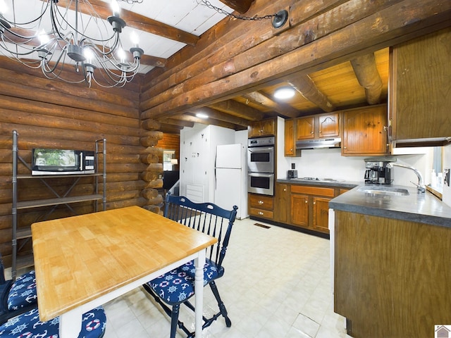 kitchen featuring appliances with stainless steel finishes, beam ceiling, sink, rustic walls, and a notable chandelier