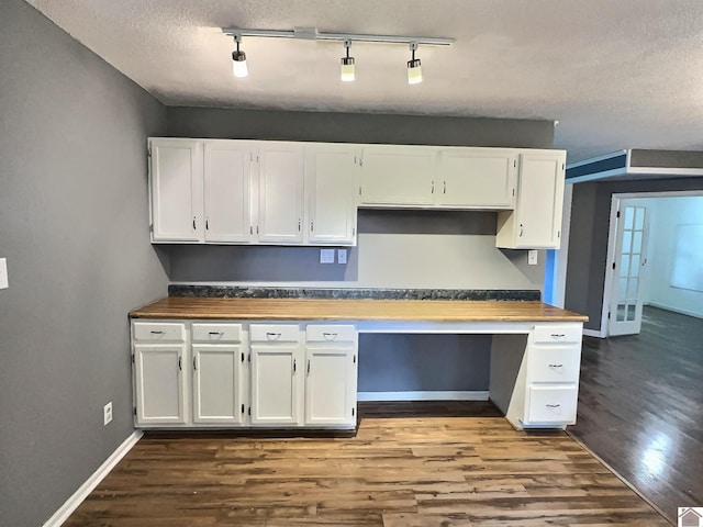 kitchen featuring wood-type flooring, built in desk, a textured ceiling, track lighting, and white cabinetry