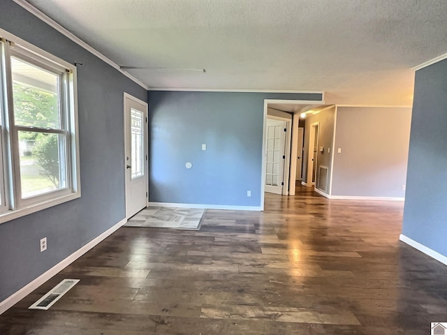 empty room featuring a textured ceiling, crown molding, and dark wood-type flooring