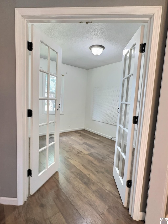 doorway to outside featuring baseboards, french doors, wood finished floors, and a textured ceiling