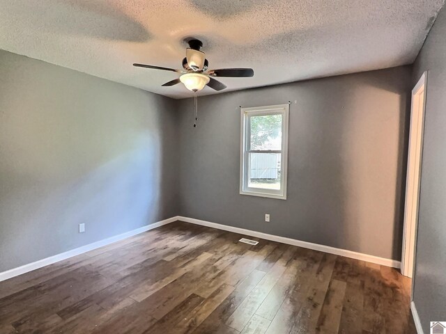 unfurnished room featuring dark wood-type flooring, a textured ceiling, ceiling fan, and visible vents