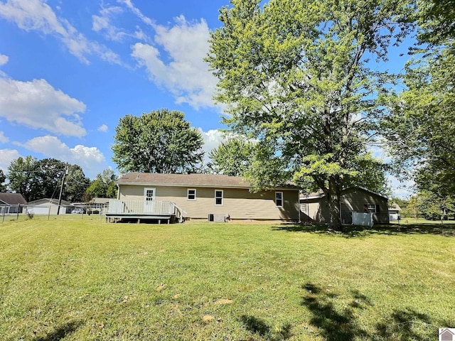 rear view of property featuring a wooden deck and a lawn